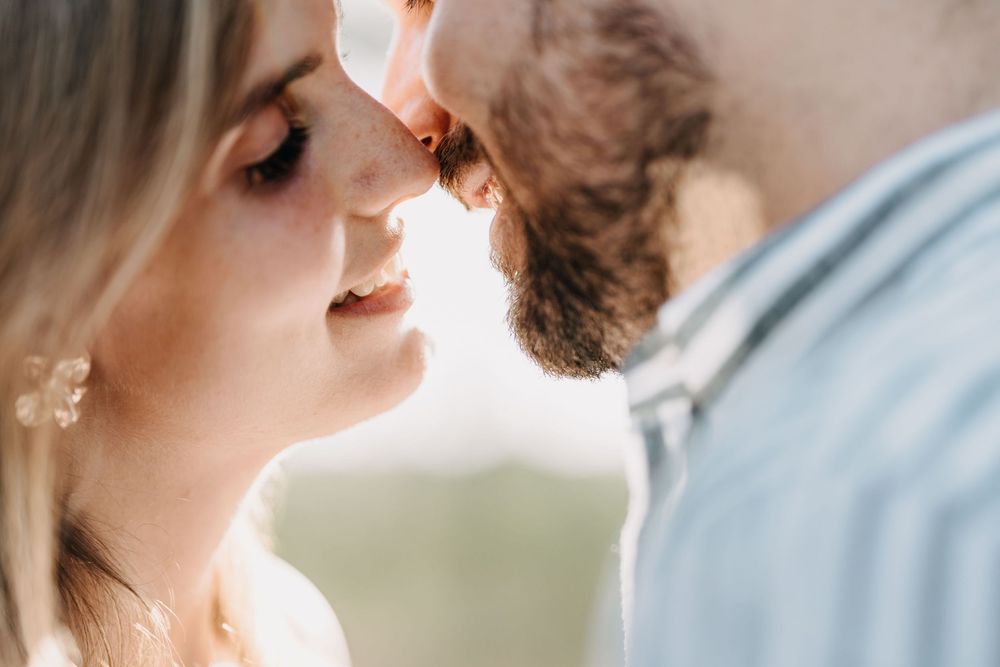 A romantic wedding couple shares an intimate moment in soft natural lighting during their outdoor ceremony.