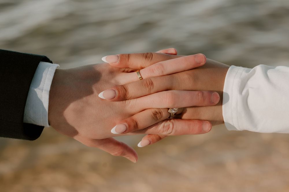 A series of hands reaching out to hold each other in a connected chain against a neutral background.