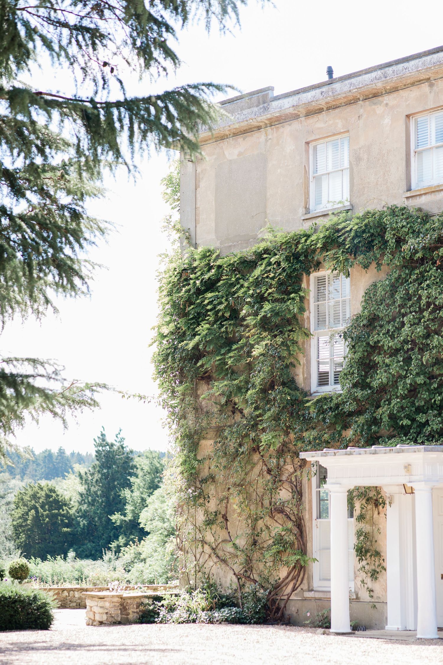 Elegant stone mansion with climbing ivy and white columns features multiple architectural views against a bright sky.