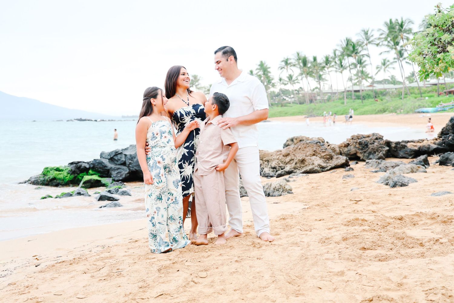 A group of people wearing coordinated blue and white outfits pose together on a sandy beach at sunset.
