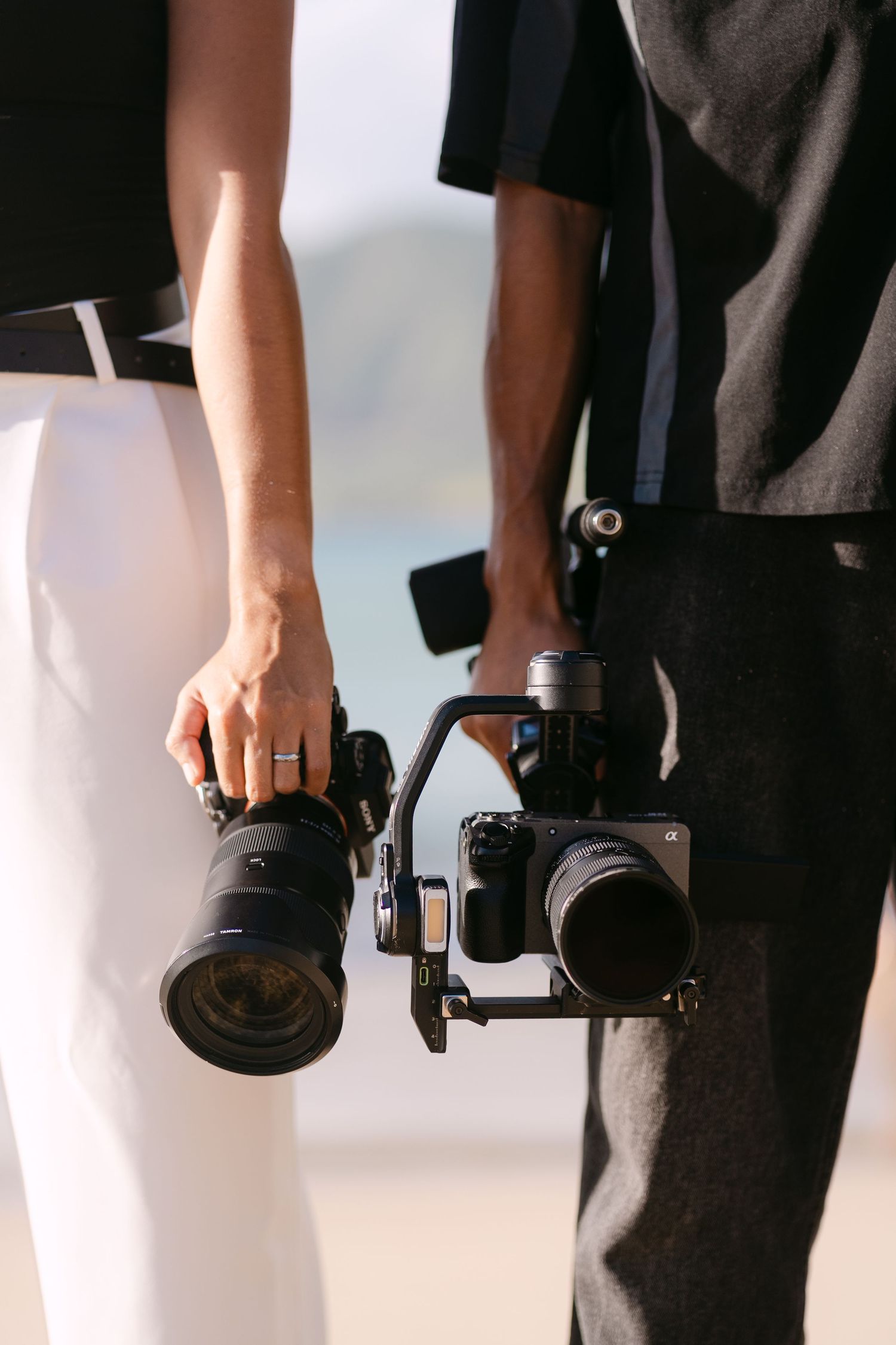 Professional photographer holding a DSLR camera with black lens against white background.