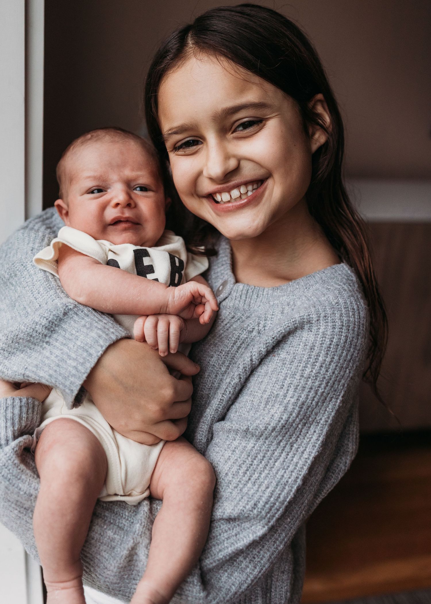 A tender moment captured in a series of photos showing a parent in a gray sweater holding and bonding with a small baby.