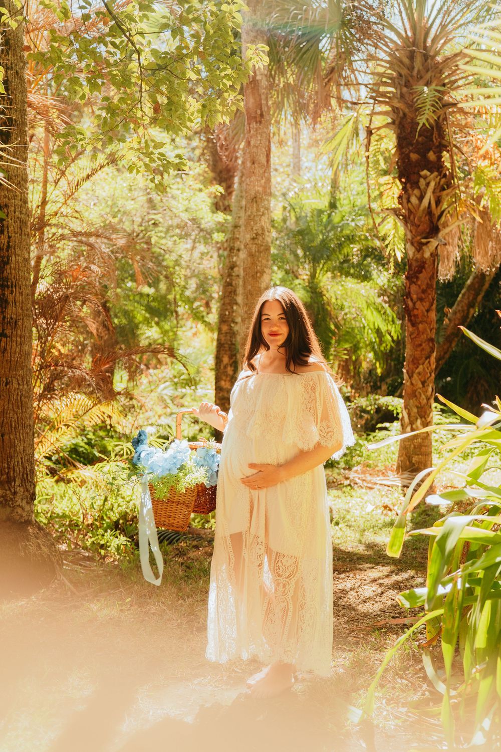 A dreamy ethereal photo series shows a figure in a flowing white dress walking through a sunlit garden with palm trees.