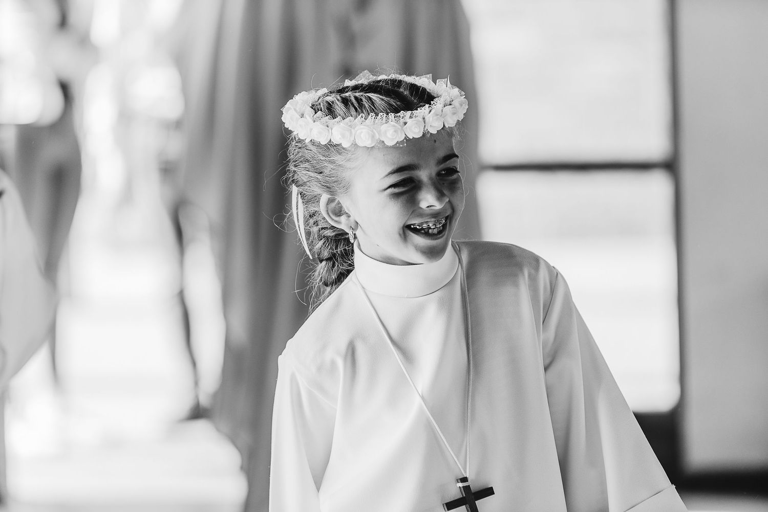 Youth in white ceremonial robe wearing floral crown during religious ceremony.