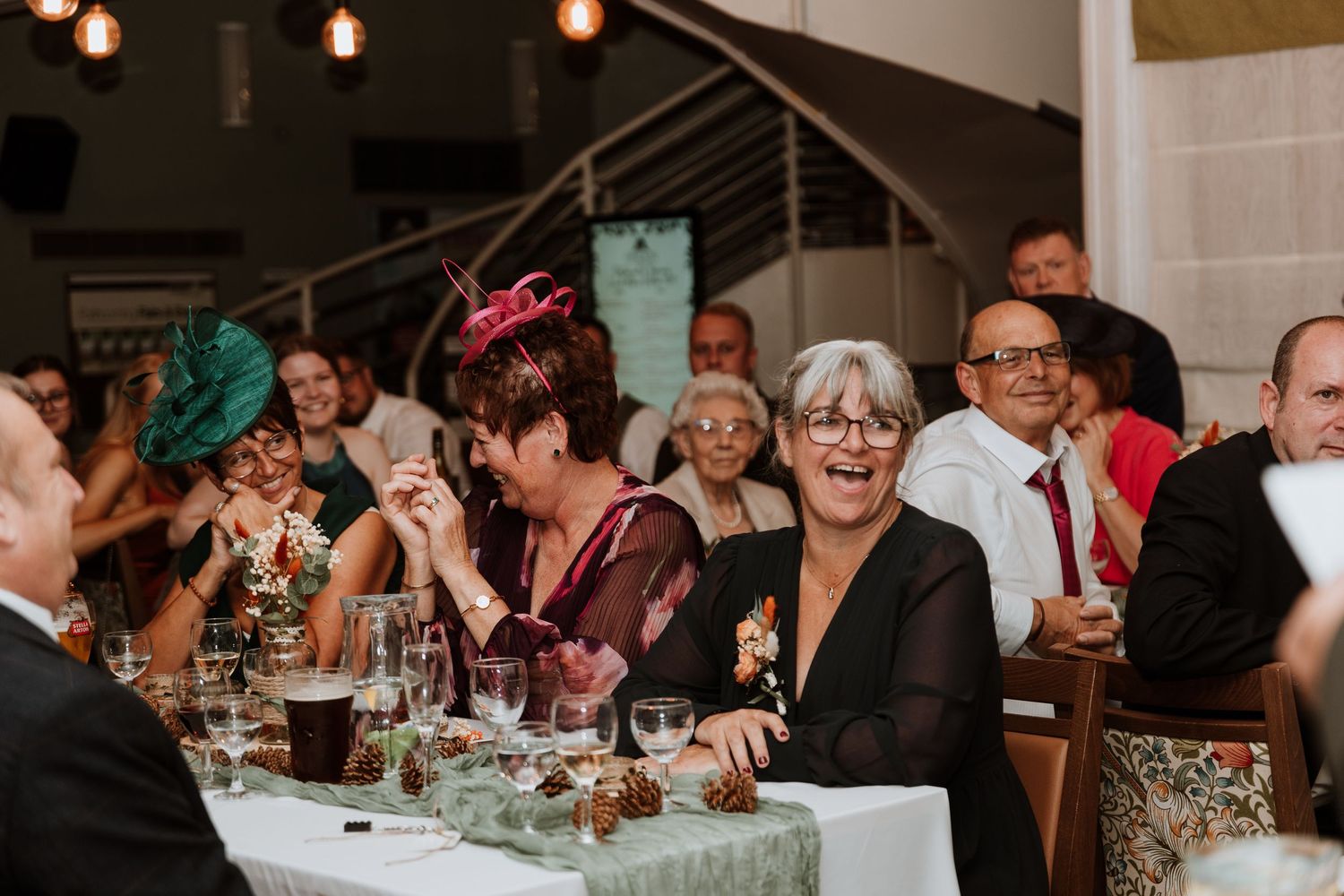 Wedding guests seated at tables during reception with decorative lighting and festive atmosphere.