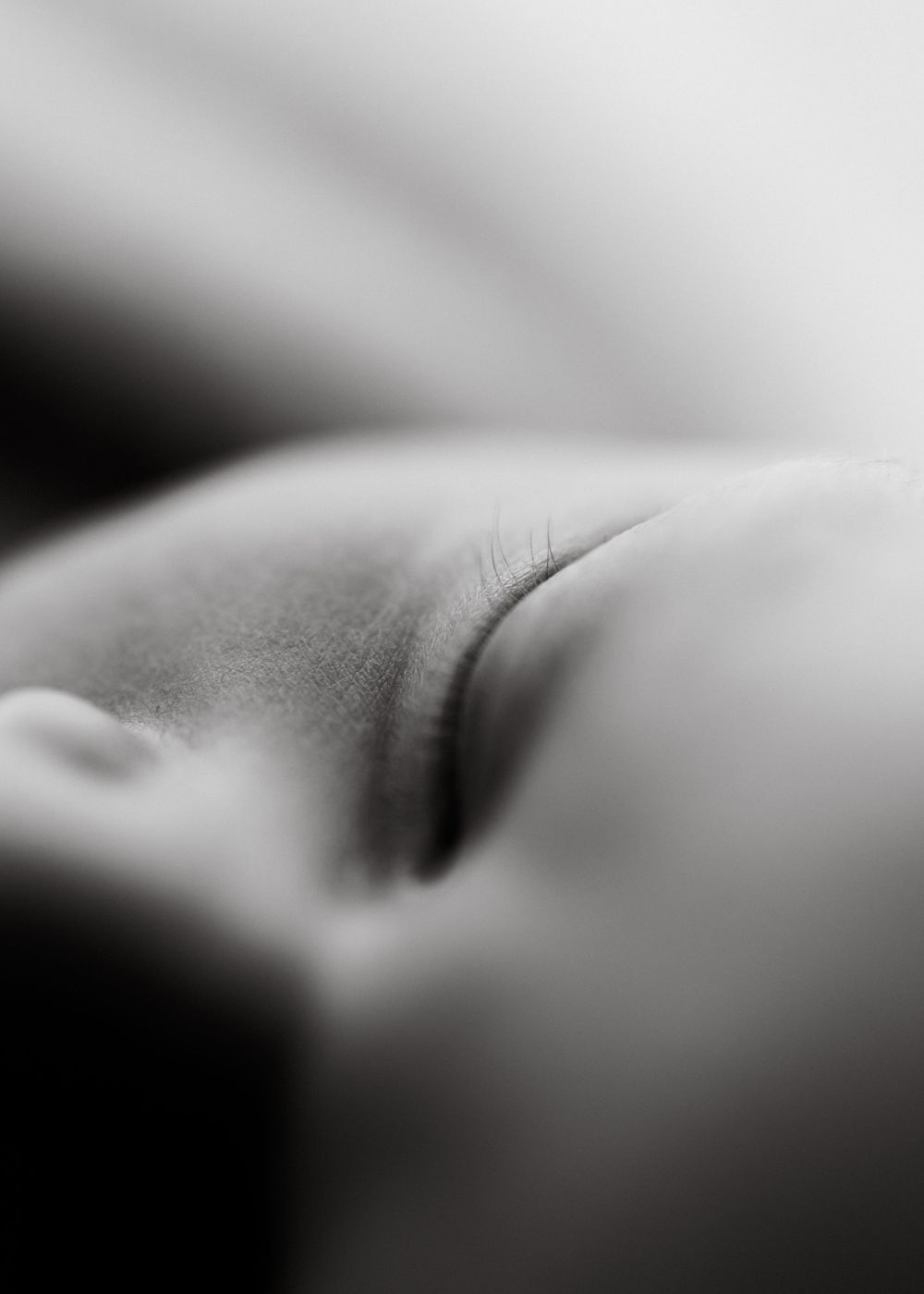 Close up black and white macro photograph showing the peaceful closed eye of a sleeping baby.