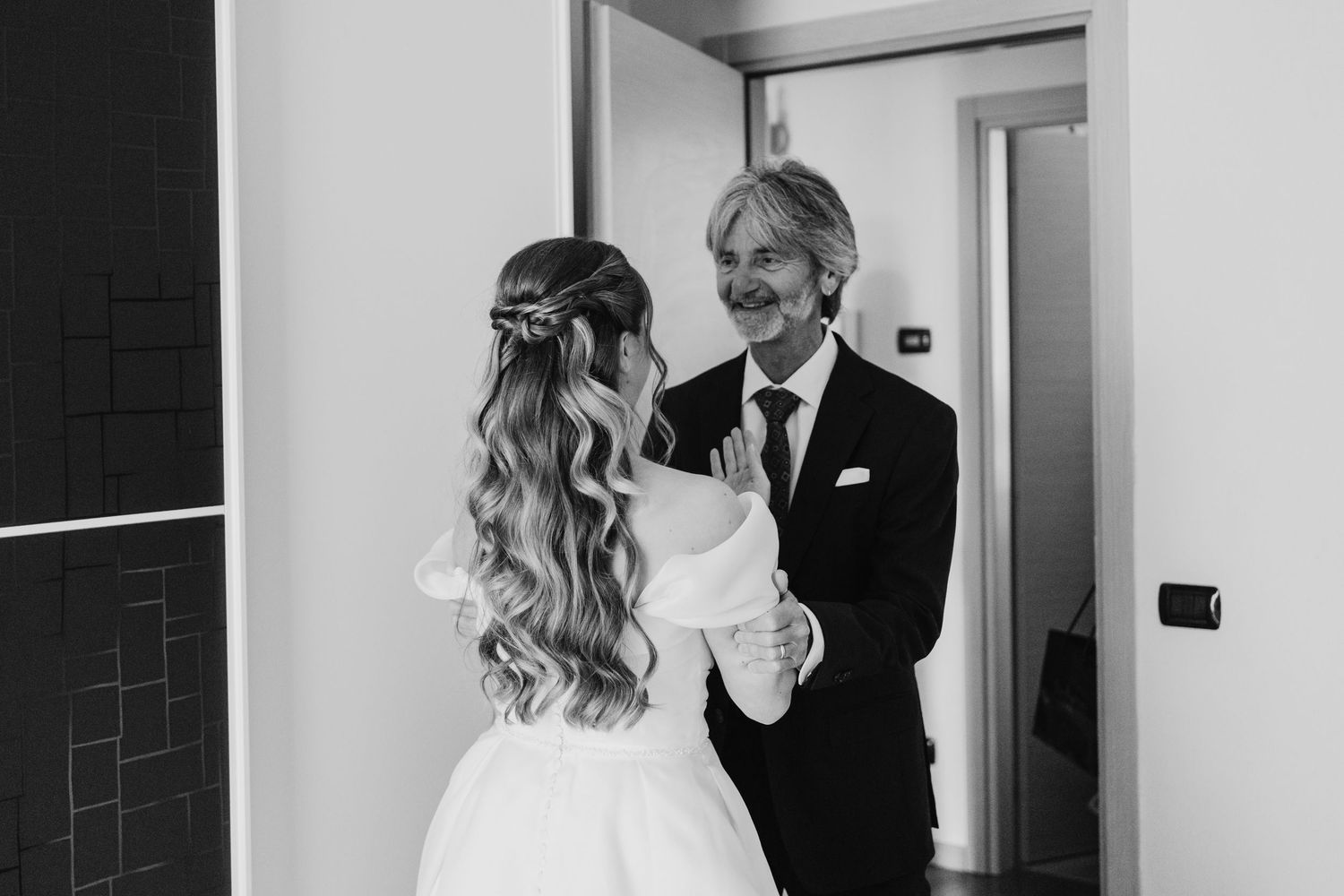Black and white photo of a smiling father seeing his bride daughter for the first time.