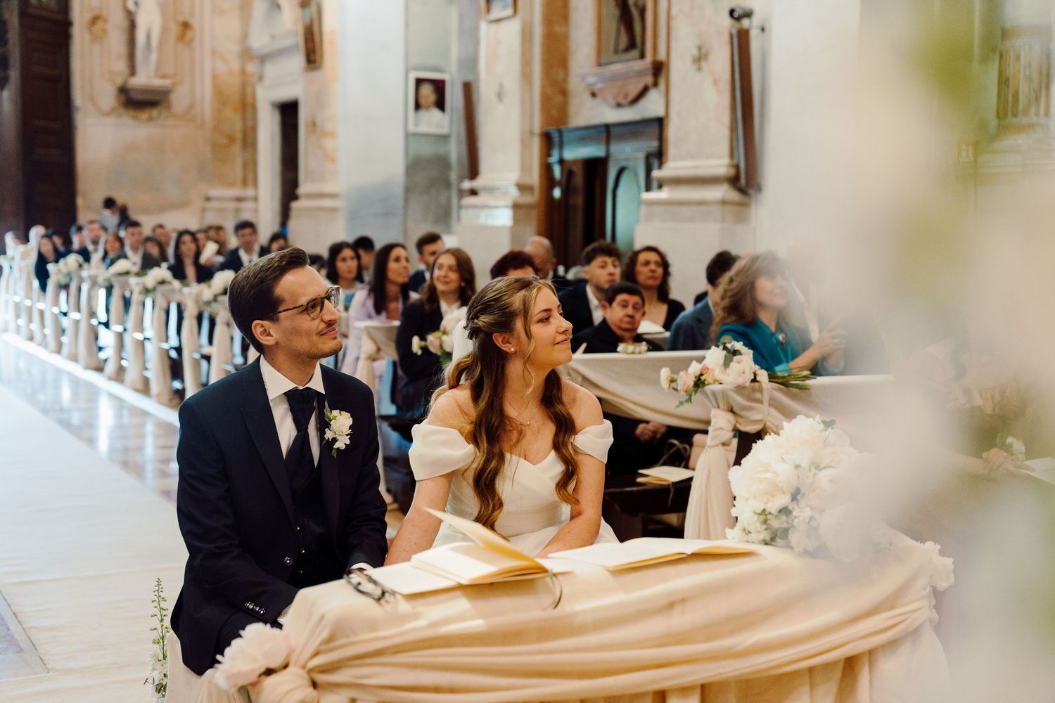Bride and groom sit together at the altar during their elegant church wedding ceremony.