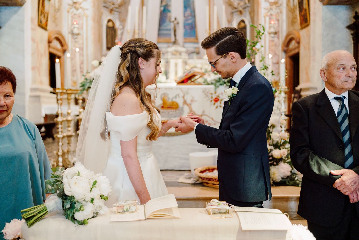 Groom places wedding ring on brides finger at the altar during church ceremony.