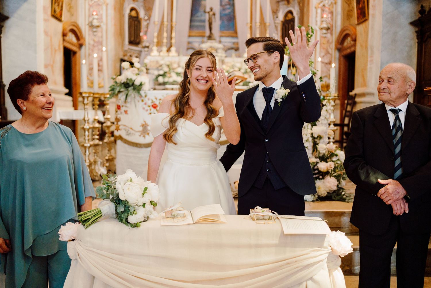 Newlyweds celebrate joyfully with family members beside the decorated church altar.
