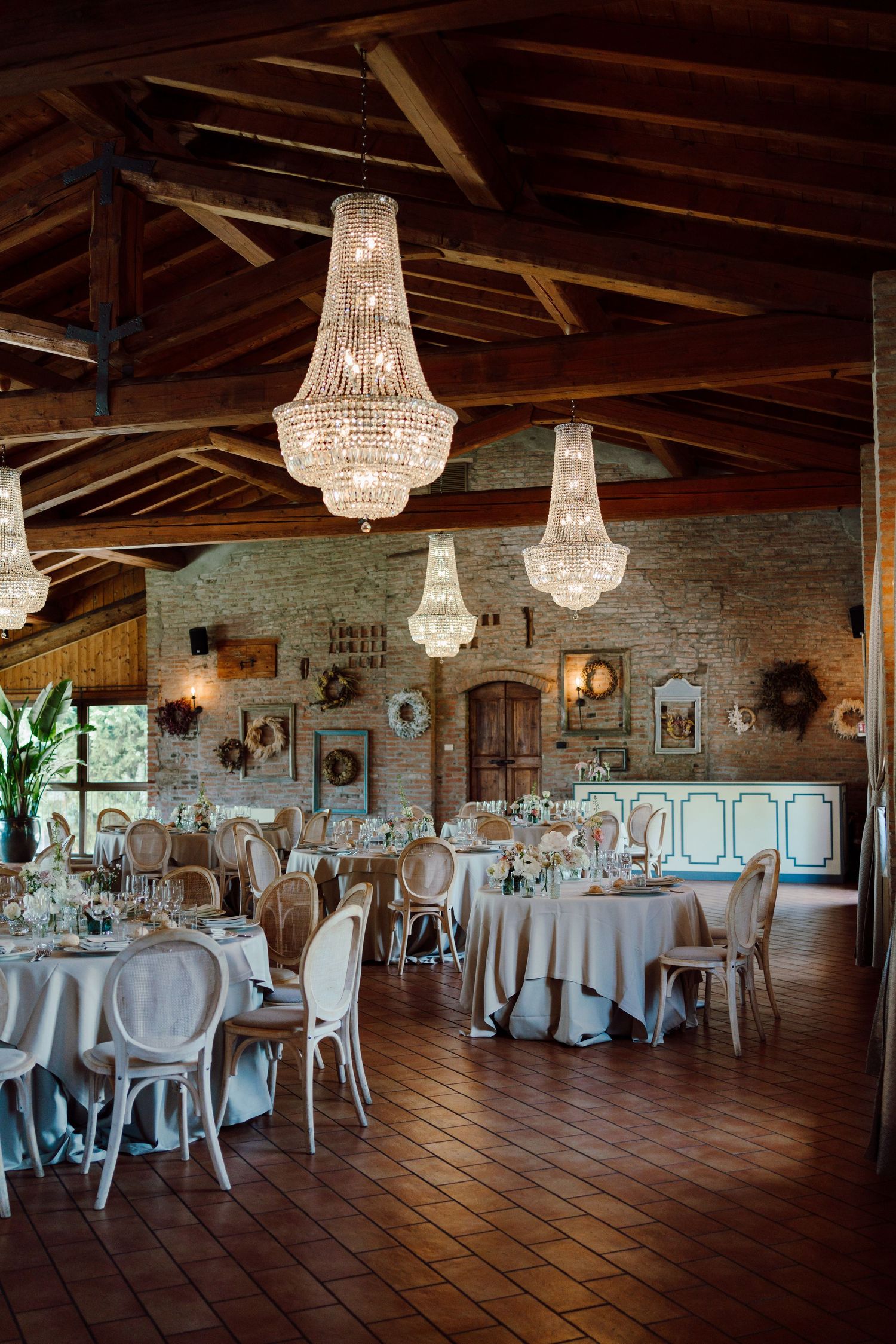 Rustic wedding reception venue with crystal chandeliers, stone walls, and elegant round tables.