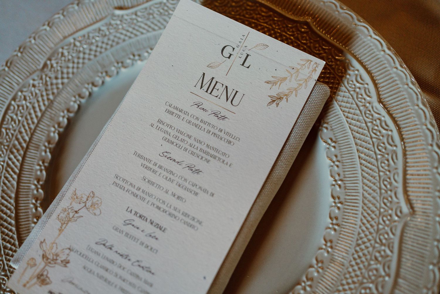 Elegant wedding menu card with floral details on a decorative charger plate.