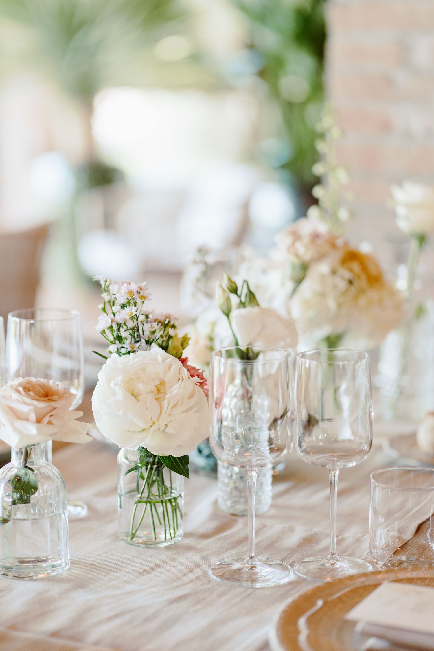 Romantic wedding table centerpiece with white peonies and blush roses in glass vases.