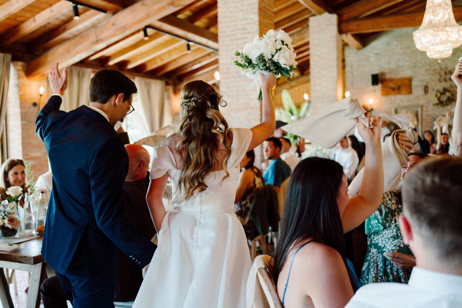Bride and groom making grand entrance at wedding reception with cheering guests.