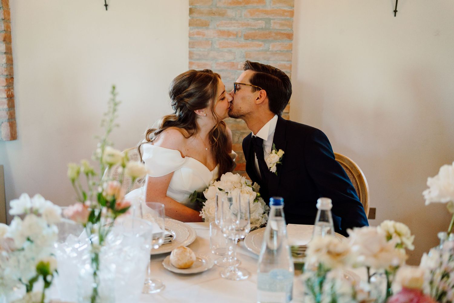 Bride and groom sharing a kiss at their wedding reception sweetheart table.