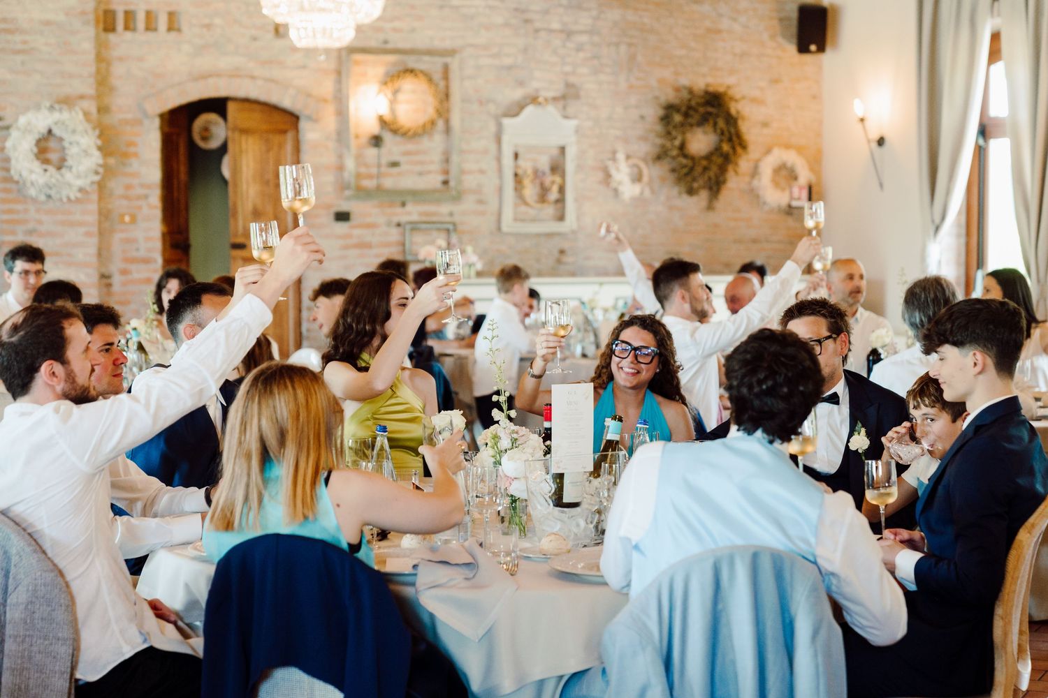 Wedding guests raising champagne glasses in a toast at a rustic reception venue.