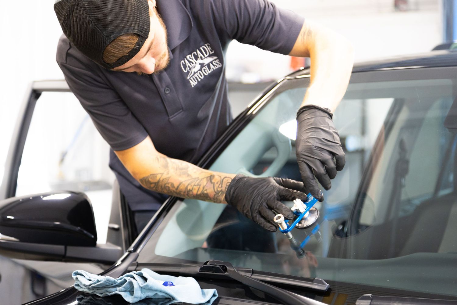 Auto detailer wearing protective gloves applies ceramic coating to a car's exterior surface with precision.