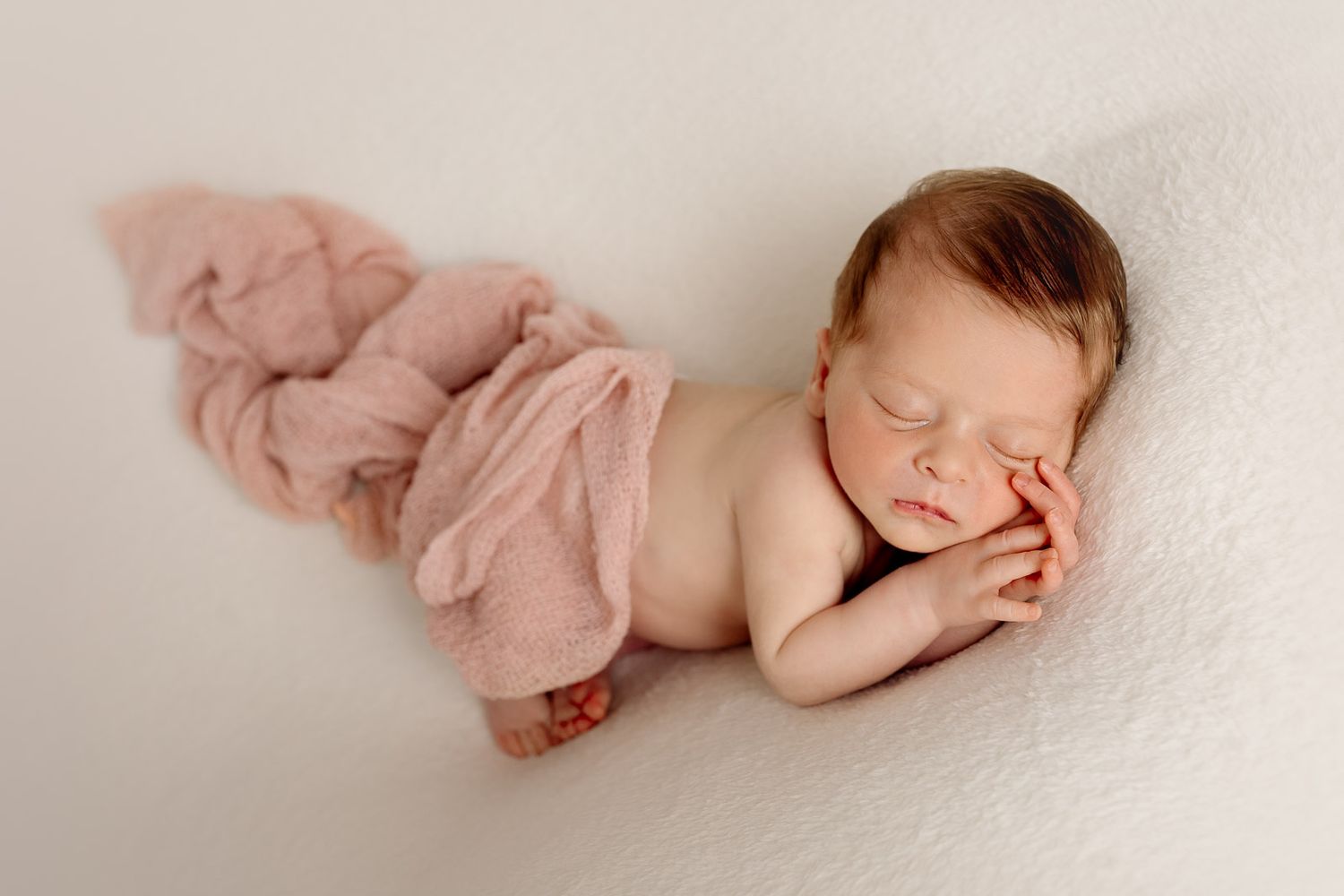 A sleeping newborn baby wearing pink lies peacefully on a white blanket in a collage of similar poses.