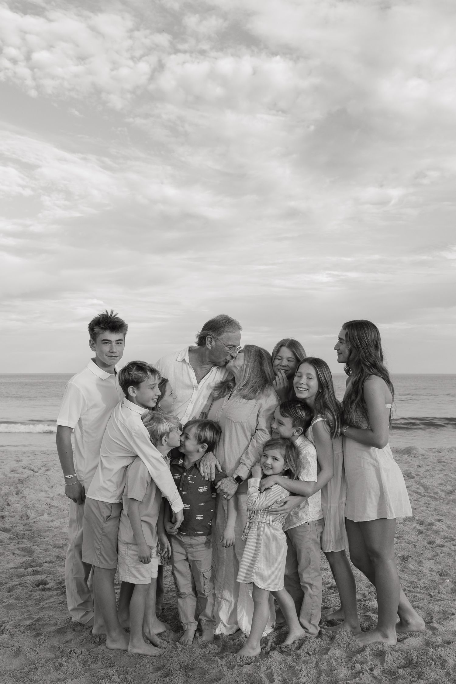 Family enjoying a playful moment together on a sunny beach with ocean waves in the background.