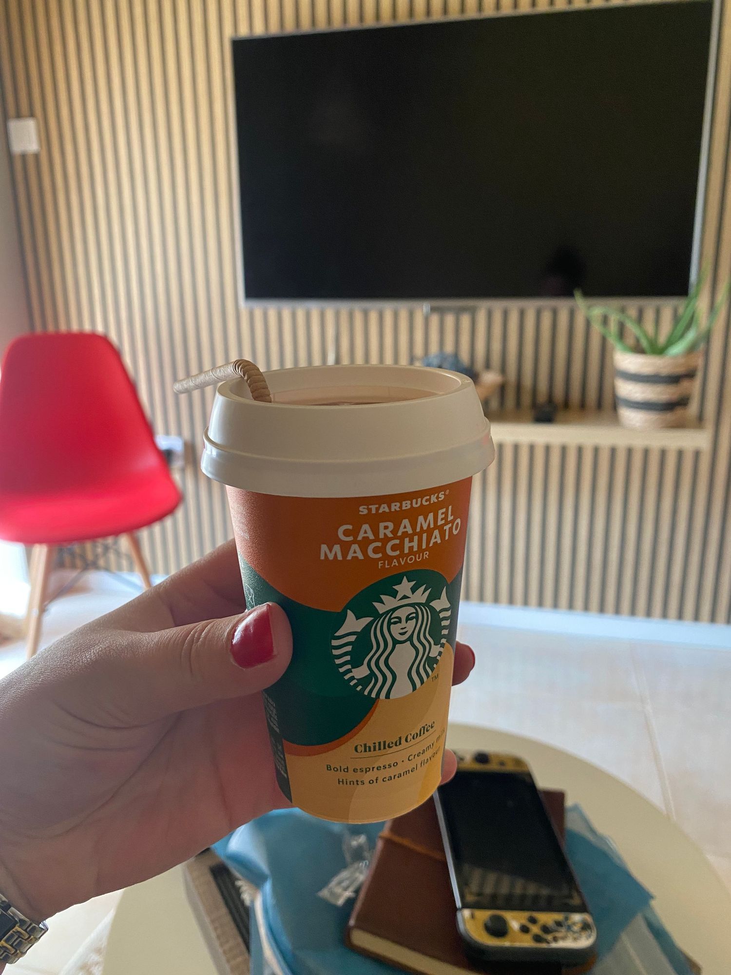 Four Starbucks caramel macchiato cups shown in sequence being held against a striped wallpaper background.