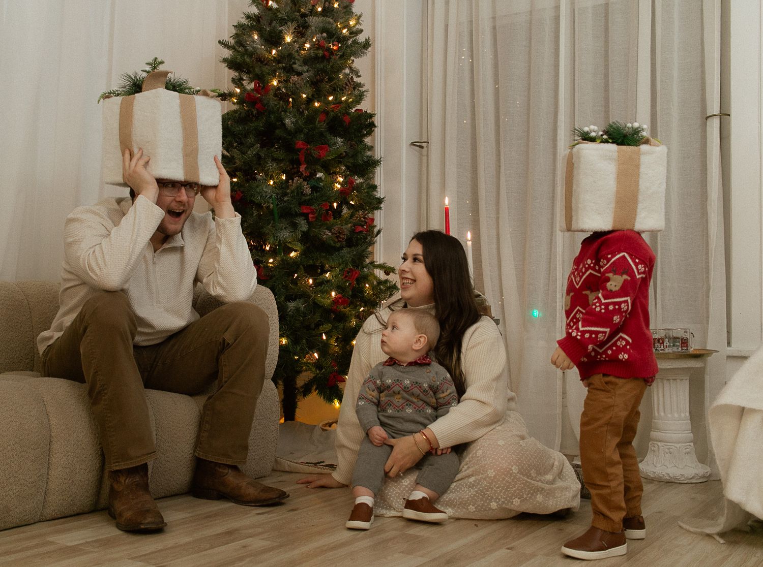 Small child in red sweater and gray pants excitedly runs toward decorated Christmas tree in living room.