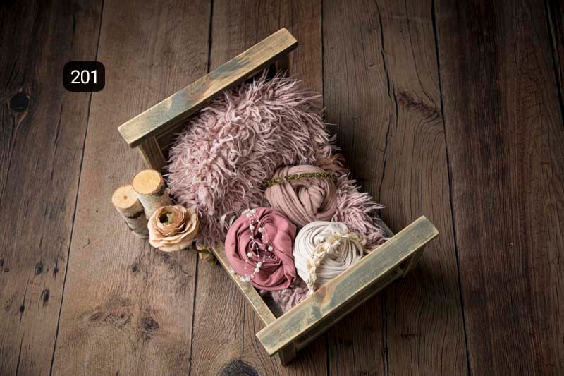 Rustic wooden backdrop with pink plush accessories and props for newborn photography.