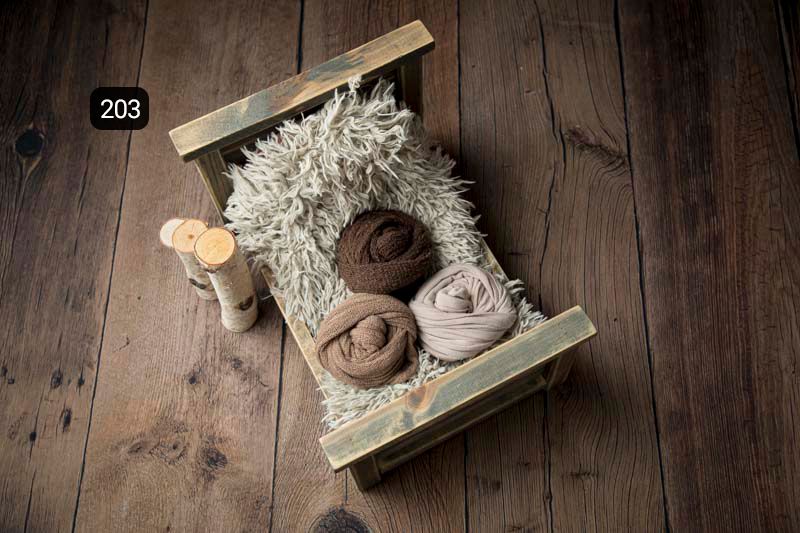 Cream colored newborn photography props arranged on weathered wood planks.