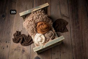 Neutral toned newborn photography props displayed on dark wooden background.