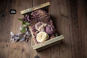 Purple and cream floral accessories styled on wooden backdrop for newborn photography.