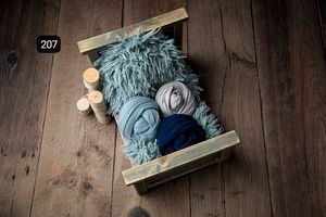 Soft blue and gray newborn photography accessories arranged on rustic wooden surface.