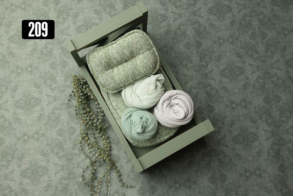 Green wooden box with sage green knit wraps and textured fabrics for newborn photography props.