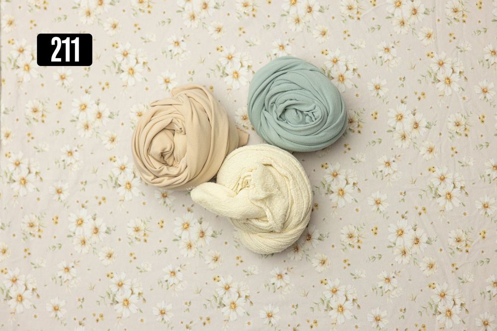 Three rolled fabric wraps in beige, sage green, and cream displayed on a floral background, labeled 211.