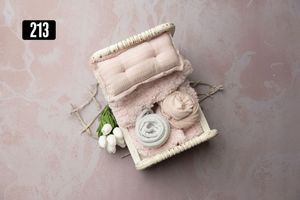 Pink newborn photography prop set with wicker basket, soft bedding, and floral accents on marble background.