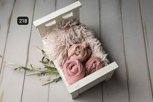 Delicate pink and cream newborn photography props styled on white wooden backdrop.