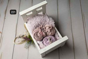 Pink and mauve fabric wraps arranged artistically on white wooden backdrop with decorative elements.