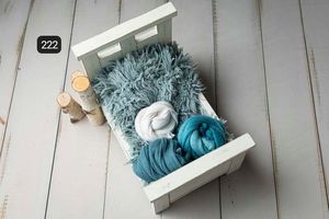 Soft blue and turquoise fabric wraps displayed on white wooden surface with natural styling.