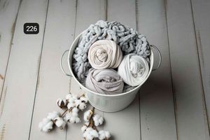 White and gray fabric wraps with cotton bolls displayed on rustic wooden background.