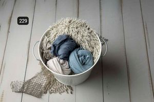Navy blue fabric wraps styled with natural elements on white wooden planks.