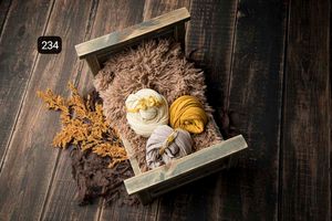 Warm golden fabric wraps and dried flowers arranged on dark wooden background.