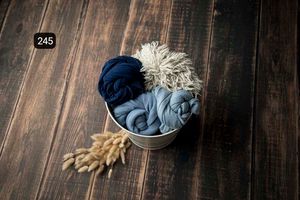 Deep navy fabric wraps styled with natural elements on dark wooden surface.