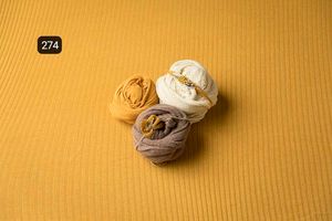 Soft fabric wraps arranged on a textured yellow background create a minimalist composition.