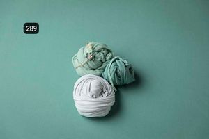 Delicate fabric wraps displayed on a mint green background in a simple arrangement.