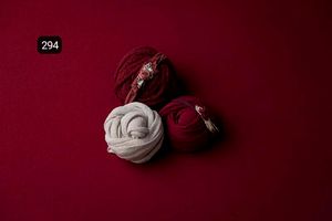 White fabric wraps artistically arranged against a deep burgundy background.