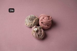 Pink and beige fabric wraps delicately arranged on a dusty rose background.