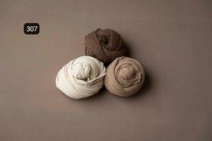 White and beige fabric wraps arranged minimally on a neutral gray surface.