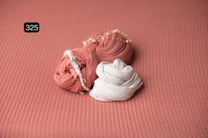 Coral and white fabric wraps displayed on textured pink background.