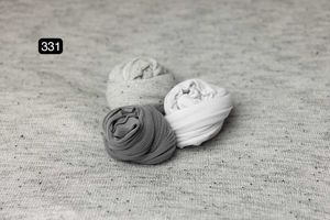 Three fabric wraps in gray and white tones arranged on a textured surface.