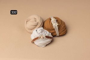 Three wrapped fabric bundles in neutral beige and white tones on a tan background.