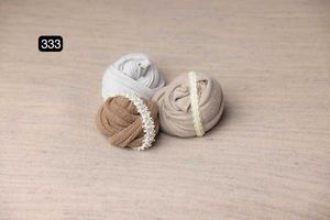 Three wrapped fabric pieces in beige and white colors on a light surface.