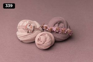 Three pink fabric wraps decorated with delicate floral elements on mauve background.